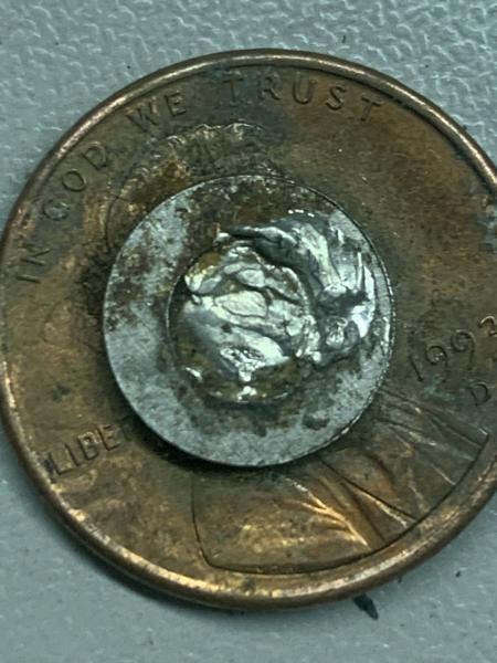 Looks like a silver planchette stuck on penny